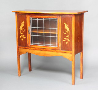 An Edwardian Art Nouveau inlaid mahogany bow front cabinet decorated mythical birds, enclosed by a lead glazed panelled door raised on square tapered supports 89cm h x 92cm x 38cm d 