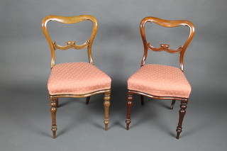 A pair of Victorian rosewood spoon back chairs with shaped mid rails and over stuffed seats, raised on turned supports (some sun bleaching) 