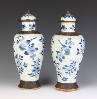 A pair of Chinese crackle glaze blue and white oviform vases and covers decorated with flowers and with shi shi finials 32cm  