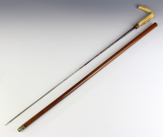 A Victorian Toledo sword stick with 69cm etched blade, gilt banded and carved horn handle decorated a buckle contained in a malacca cane 