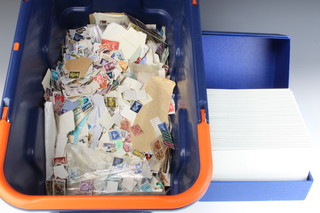 A blue and orange plastic crate containing a collection of loose world stamps etc 