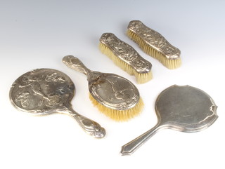 An Art Nouveau silver 4 piece repousse brush set decorated with cavorting cherubs comprising 1 hair brush, 2 clothes brushes and a mirror Birmingham 1905 together with a silver backed hand mirror 