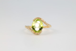 A 14ct yellow gold oval cut peridot and diamond ring, the centre stone approx. 2.4ct flanked by brilliant cut diamonds 0.3ct size M 1/2