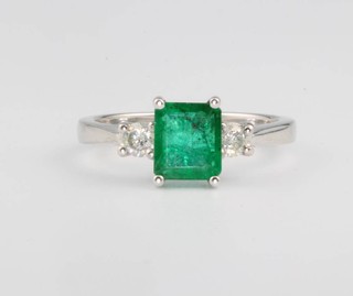 An 18ct white gold emerald and diamond ring, the centre stone approx. 0.96ct, flanked by 2 brilliant cut diamonds approx. 0.22ct, size M 