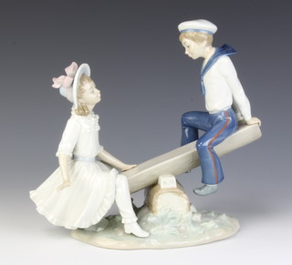 A Lladro group of a boy sailor and girl on a log seesaw 24cm 