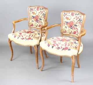 A pair of French open arm salon chairs with Berlin woolwork seats and backs, raised on cabriole supports