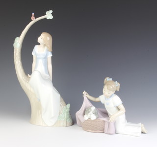 A Nao figure of a lady sitting on a tree trunk beneath a bird 32cm and a ditto figure of a girl with a dog in a basket 