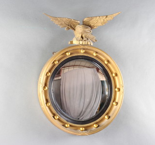 A Regency style circular convex plate wall mirror contained in a gilt ball studded frame surmounted by a figure of an eagle with wings outstretched  43cm 