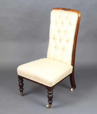 A Victorian mahogany show frame nursing chair raised on turned supports upholstered in yellow buttoned material