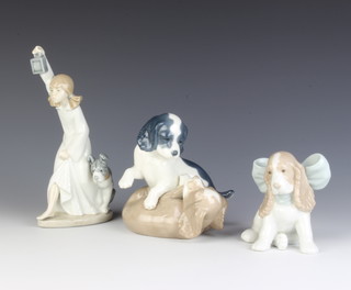 A Nao figure of a Spaniel puppy wearing a bow 11cm, a ditto figure of a girl with a dog holding a lantern 22cm and a ditto figure of 2 puppies play fighting 14cm 