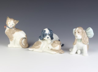 A Nao group of 2 puppies 10cm, a ditto of a Spaniel puppy with a bow 10cm and another of a cat 10cm 