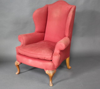 A Queen Anne style winged armchair upholstered in red material, raised on cabriole supports 