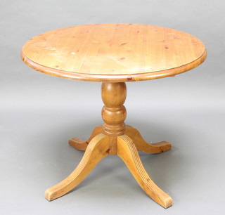 A circular pine pedestal table raised on a turned column and tripod base 73cm x 89cm 