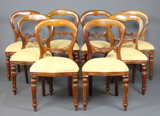 A near matched set of 8 Victorian style mahogany balloon back dining chairs with carved mid rails and over-stuffed seats, raised on turned and fluted supports 