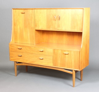 A 1960's G-Plan teak sideboard, the raised back fitted a cocktail unit and cupboard enclosed by panelled doors, the base fitted 2 long drawers flanked by a cupboard 136cm h x 63cm w x 43cm d 
