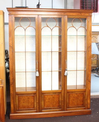 A Georgian style walnut display cabinet with moulded cornice, fitted adjustable shelves enclosed by astragal glazed panelled doors and raised on a platform base 201cm h x 156cm w x 38cm d