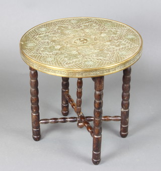 An embossed circular brass tray raised on a folding oak bobbin turned stand 58cm h x 61cm diam. 