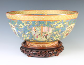 A modern famille rose porcelain bowl decorated with panels of figures in pavilions and flowers 35cm, with wooden stand