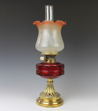 A Victorian oil lamp with embossed brass base and ruby glass reservoir, clear glass chimney and opaque glass shade 
