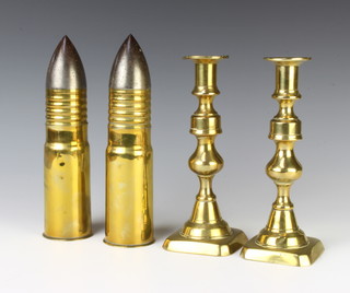 2 First World War shells complete with polished steel nose cones 23cm x 6cm together with a pair of 19th Century brass candlesticks 21cm 