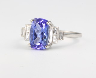 An 18ct white gold oval tanzanite and diamond ring, the centre stone approx. 2.8ct flanked by baguette cut diamonds approx. 0.35ct, size N 1/2