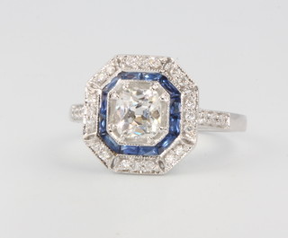 An 18ct white gold Art Deco style sapphire and diamond ring, the centre stone approx. 0.67ct surrounded by sapphires and diamonds, size N