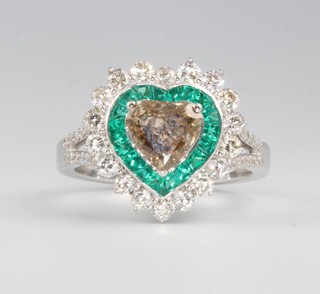 An 18ct white gold heart shaped diamond and emerald ring, the centre stone approx 1.22ct, surrounded by emeralds 1.89ct and brilliant cut diamonds 0.98ct, size O 