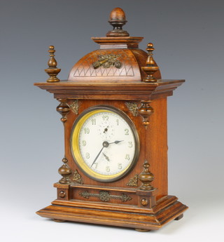 Junghams, a German alarm clock with paper dial and Arabic numerals, alarm dial and subsidiary dial contained in a carved oak case 