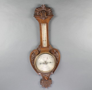 An Edwardian aneroid barometer and thermometer, the silvered dial marked James Lucking & Co Opticians 5 Coronation Street Birmingham, contained in a carved oak wheel case 