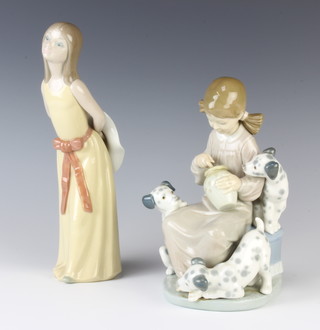 A Lladro group of a girl with 3 Dalmatian puppies 20cm and a ditto of a standing girl holding a hat behind her back 24cm 