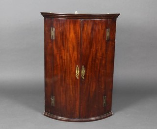 A Georgian mahogany bow front hanging corner cabinet with moulded cornice, fitted shelves enclosed by panelled doors 170cm x 48cm 