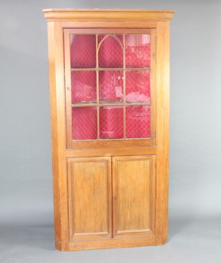 A Victorian pine double corner cabinet, the upper section with moulded cornice, the interior fitted shelves enclosed by astragal glazed panelled doors, the base fitted a cupboard enclosed by a panelled door, raised on a platform base 214cm h x 112cm w x 60cm d 