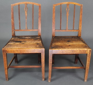 A pair of 18th Century elm stick and rail back hall chairs with solid seats raised on squared supports