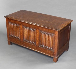 A 1930's oak coffer with hinged lid and linen fold decoration, raised on square supports 47cm h x 92cm w x 43cm d 