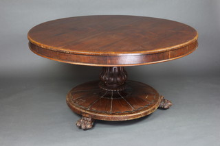 A William IV circular rosewood snap top pedestal dining table raised on a turned column and circular base with paw feet 72cm h x 140cm diam. 