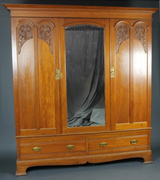 Maple and Co. an Edwardian Art Nouveau carved satinwood wardrobe, the moulded cornice with pierced panel above, fitted a mirror flanked by a pair of arched carved panelled doors, the base fitted 2 long drawers raised on bracket feet 238cm h x 195cm w x 60cm d  
