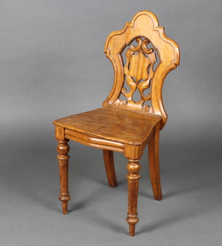 A Victorian light oak shield back hall chair with solid seat, raised on turned supports