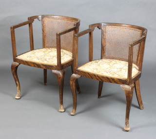 A pair of Edwardian mahogany tub back chairs with woven cane panels and upholstered seats, on cabriole supports