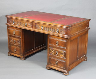 An oak kneehole desk with inset red leather writing surface above 2 long drawers, the pedestals fitted 6 short drawers, raised on bun supports 79cm h x 138cm x 76cm 