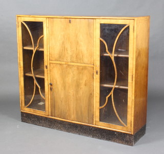 A 1930's Art Deco walnut student's bureau with fall front above a cupboard flanked by a pair of cupboards enclosed by astragal glazed panelled doors 105cm h x 120cm w x 31cm d 