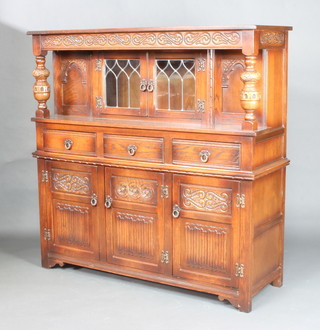 An Old Charm carved oak court cupboard the upper section enclosed by lead glazed panelled doors, the base fitted 2 drawers above a double cupboard with linen fold decoration 137cm x 138cm w x 46cm d 