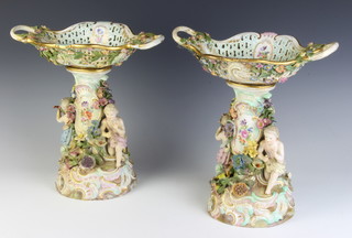 A pair of late 19th Century Meissen centrepieces with 2 handled pierced baskets encrusted with flowers on a floral encrusted support, the base with putti playing instruments on a Rococo base 30cm 
