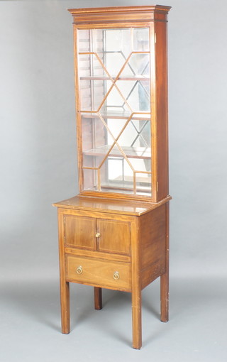 An Edwardian inlaid mahogany display cabinet with moulded cornice and mirrored back, fitted adjustable shelves enclosed by astragal glazed panelled doors, the base fitted a double cupboard above 1 long drawer, raised on square tapered supports 186cm h x 53cm w x 45cm d, the base formerly a commode