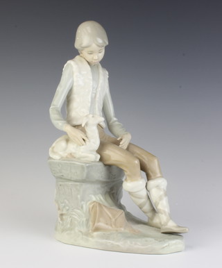 A Nao figure of a seated boy shepherd with a lamb beside him 27cm 