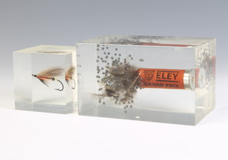 A Perspex paperweight the interior set a fired Ealing shotgun cartridge 8cm x 12cm x 7cm and 1 other set a fly 6cm x 6cm x 6cm 