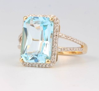 A 14ct yellow gold emerald cut blue topaz ring, approx 6.2ct surrounded by brilliant cut diamonds approx. 0.5ct size M 1/2