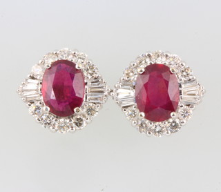 A pair of 18ct white gold oval ruby and diamond ear studs, the treated centre stones approx. 3.19ct, flanked by baguette diamonds approx. 0.26ct brilliant cut diamonds approx 0.87ct