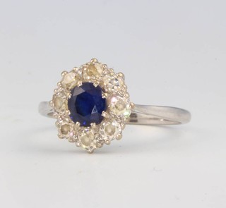 A white gold sapphire and diamond cluster ring the centre stone approx 0.7ct flanked by 8 brilliant cut diamonds approx. 0.10ct each size Q