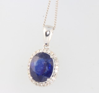 A white gold oval sapphire and diamond pendant on a 9ct white gold chain (the sapphire has been colour treated) 