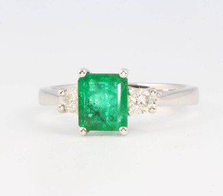 An 18ct white gold emerald and diamond ring the centre stone approx. 0.9ct flanked by 2 diamonds approx. 0.22ct size M 
